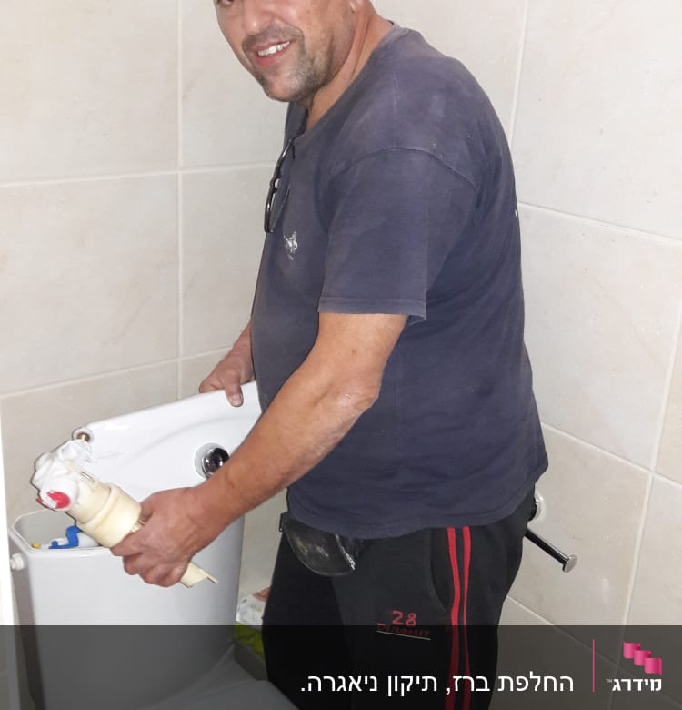 אדם מחזיק חלקים של אסלה בשירותים